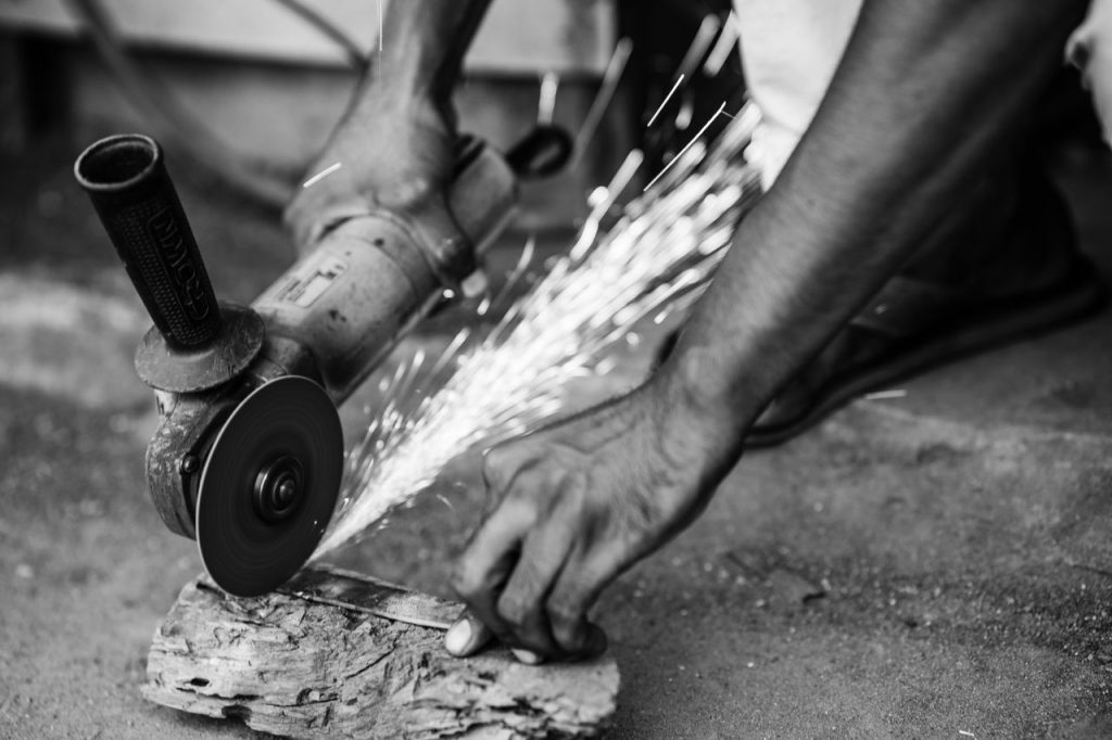 A skilled worker uses an angle grinder, creating sparks, showcasing craftsmanship in Bangladesh.