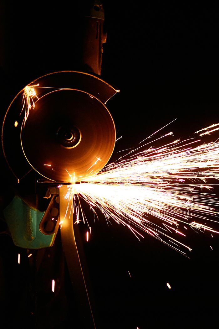 Close-up of an angle grinder in action, producing vibrant sparks against a dark background.